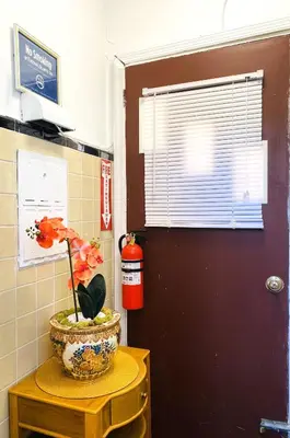 a flower in a vase on a table next to a door at NYC cozy room in Van Nest