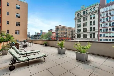 a balcony with benches and tables and buildings at Stunning NYC Views! Free Gym! Doorman! Terrace! in New York
