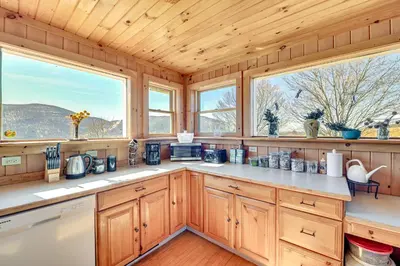 a kitchen with wooden cabinets and two windows at 3 Mi to Catskill Trail Stamford Cottage with Views in Stamford
