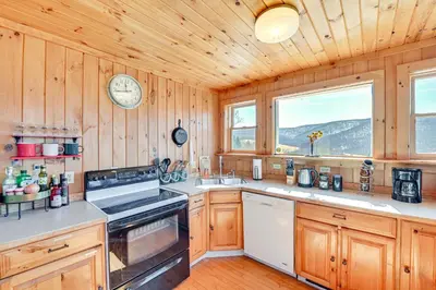a kitchen with wooden cabinets and a clock on the wall at 3 Mi to Catskill Trail Stamford Cottage with Views in Stamford