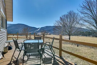 a table and chairs on a deck with a view of a field at 3 Mi to Catskill Trail Stamford Cottage with Views in Stamford