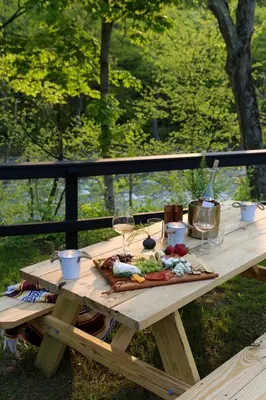 a picnic table with wine glasses and food on it at Perch Cottages #3 - Creek Access, Sauna, Mt views in Boiceville
