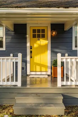 a yellow door on the front of a blue house at Perch Cottages #5 - Creek Access, Sauna, Mt views in Boiceville