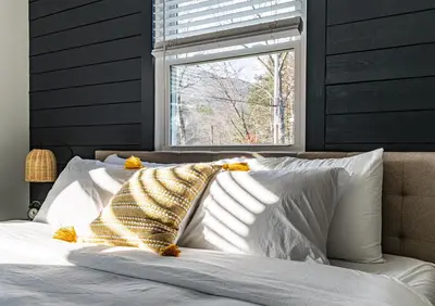 a bed with a blanket on it with a window at Perch Cottages #5 - Creek Access, Sauna, Mt views in Boiceville