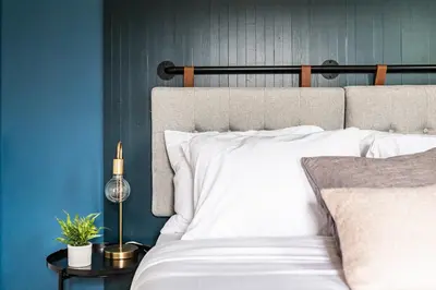 a bedroom with a white bed with a blue wall at Perch Cottages #9 - Creek Access, Sauna, Mt views in Boiceville