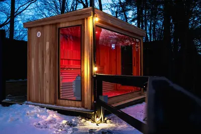 a small wooden cabin with lights in the snow at Perch Cottages #9 - Creek Access, Sauna, Mt views in Boiceville