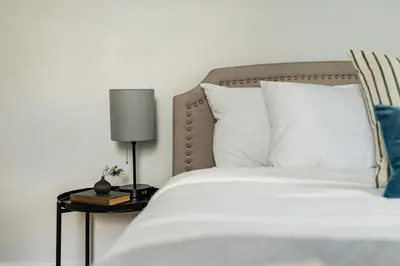 a bed with white sheets and a lamp on a table at Perch Cottages #11 - Creek Access, Sauna, Mt views in Boiceville