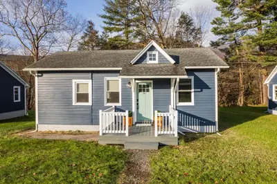 a blue house with a porch with a green door at Perch Cottages #11 - Creek Access, Sauna, Mt views in Boiceville