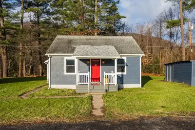 a small house with a red door in a yard at Perch Cottages #15 - Creek Access, Sauna, Mt views in Boiceville