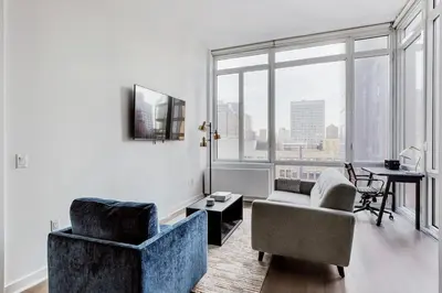 a living room with a couch and a chair and a table at Blueground Midtown S gym AC nr Empire St NYC-1591 in New York