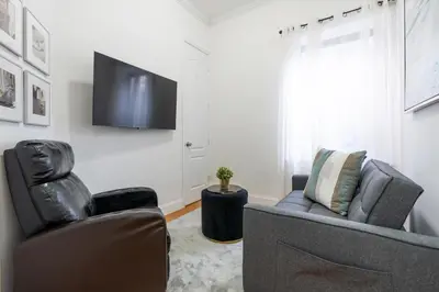 a living room with two chairs and a flat screen tv at Prestige NYC Suite in New York
