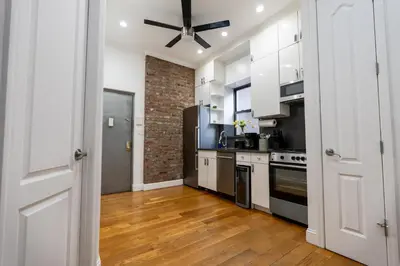a kitchen with white cabinets and a brick wall at Prestige NYC Suite in New York