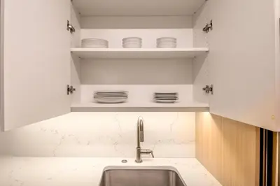a kitchen with a sink and plates on shelves at UWS 1BR w WD nr Lincoln Center NYC-1187 in New York