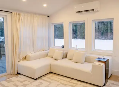 a living room with a white couch and windows at Peaceful Catskills Creek House in Saugerties