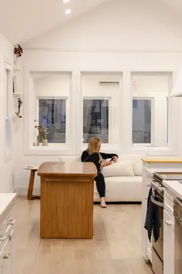 a woman sitting on a couch in a living room at Peaceful Catskills Creek House in Saugerties