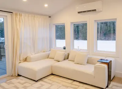 a living room with a white couch and windows at Peaceful Catskills Creek House in Saugerties