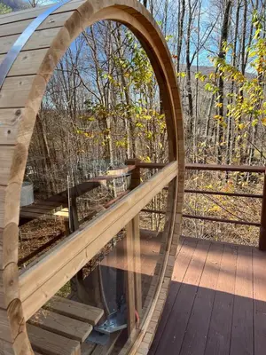 a circular window on a wooden deck with trees in the background at Colonels Cabin Sauna, Fireplace, Mountain Views in Lanesville
