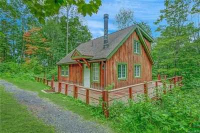 a small cabin in the woods with a fence around it at Colonels Cabin Sauna, Fireplace, Mountain Views in Lanesville