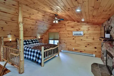a log cabin bedroom with a bed and a ceiling fan at Colonels Cabin Sauna, Fireplace, Mountain Views in Lanesville