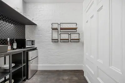 a kitchen with white brick walls and a white door at The Perfect Apt for Large Groups Sleeps 10 in New York