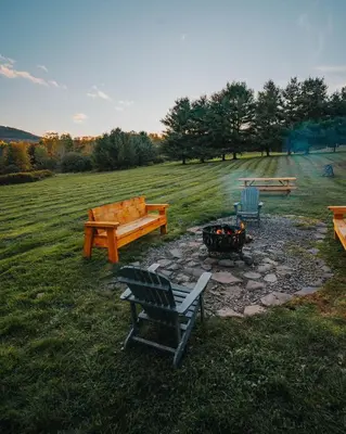 a fire pit in a field with benches and a grill at Idyllic Mountain Stay Hot Tub, Wood Stove, Games in Windham