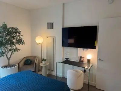 a bedroom with a blue bed and a tv on the wall at NEWLuxe 2bd2ba w Pool & More in Hoboken