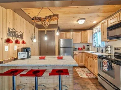 a kitchen with wooden cabinets and red bar stools at Cabin Retreat with Hot Tub in Pocono Country Place