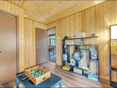 a room with wood paneled walls and a room with a table and games at Cabin Retreat with Hot Tub in Pocono Country Place