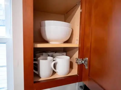 a cupboard with bowls and mugs in it at New 4 Apts-198-3 Bed Apt 1st Floor & 3 Bed Apt 2nd Floor - 1 Bed Studio Apt Ground Floor & 1 Bed Studio Apt Ground Floor near Penn Station EWR Newark NJ Airport Hospital Manhattan NYC in Newark