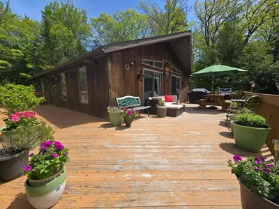 a wooden deck with potted plants and a building at Kaaterskill Waterfall House in Haines Falls