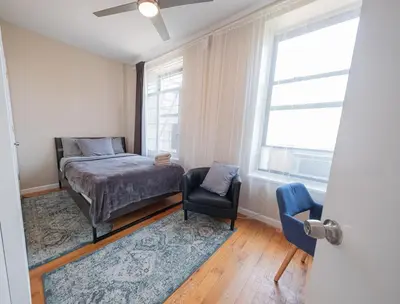 a bedroom with a bed and a chair and a window at 3BR apt two blocks to Central Park elevator, laundry, virtual doorman in New York