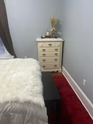 a bedroom with a dresser and a bed with a white blanket at Eden's Lodge in East Hartford