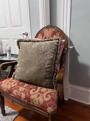 a pillow sitting on a chair next to a table at Eden's Lodge in East Hartford