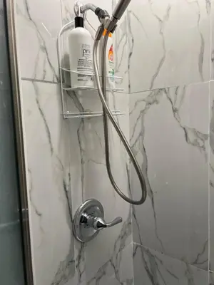 a shower with a hose attached to a marble wall at Eden's Lodge in East Hartford