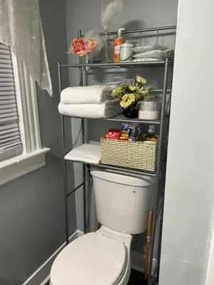 a bathroom with a toilet and a shelf with towels at Eden's Lodge in East Hartford