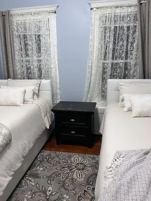 a bedroom with two beds and a nightstand between two windows at Eden's Lodge in East Hartford