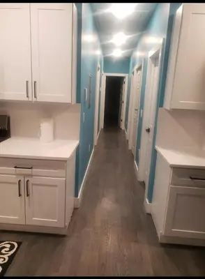 a kitchen with white cabinets and blue walls and a hallway at Comfy 3 bedroom house in Newark