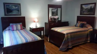 a bedroom with two beds and two tables and a mirror at The Woodridge Retreat in Goshen