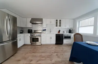 a kitchen with white cabinets and stainless steel appliances at Croton Quarters - Comfortable Apartments, NYC close in Croton-on-Hudson