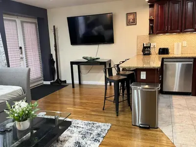 a living room with a kitchen with a table and a tv at NY - NJ Tennis Suites - Sleeps 40 - 15 Mins to NYC in Union City