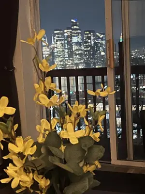 a vase filled with yellow flowers in front of a window at Triple See NY Now - Sleeps 41 -15 Mins to NYC in Union City