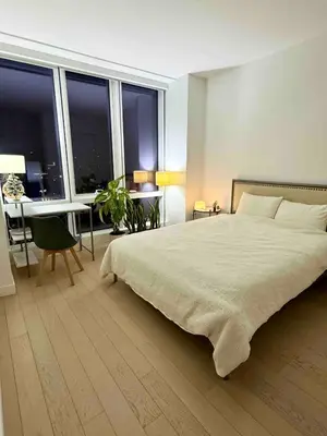 a bedroom with a large bed and a table with a tableasonable at 1 Stop to Midtown Amazing View Luxury High Rise Corner 1 Bedroom Apartment in Sunnyside