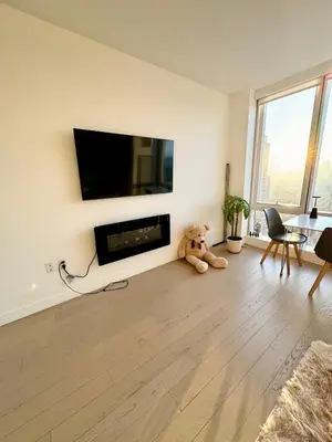 a teddy bear sitting on the floor in a living room at 1 Stop to Midtown Amazing View Luxury High Rise Corner 1 Bedroom Apartment in Sunnyside