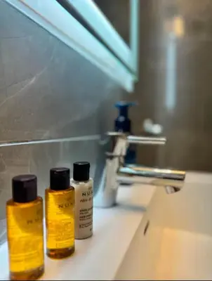 three bottles of moisturizers sitting on a bathroom sink at NEW Modern 2BR w Fireplace & Fitness Lounge, Live Comfortably in East Harlem in New York