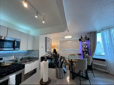 a kitchen with a table and a dining room at NEW Modern 2BR w Fireplace & Fitness Lounge, Live Comfortably in East Harlem in New York