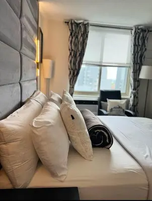 a hotel room with a bed with white pillows at NEW Modern 2BR w Fireplace & Fitness Lounge, Live Comfortably in East Harlem in New York