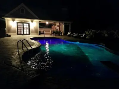 a swimming pool lit up at night at Glamorous Cottage Rental with Outdoor Lounge and Pool on 40 Acres in Pine Bush, New York in Pine Bush