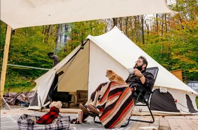 a man sitting in a chair in front of a tent at Piebald Mountain Pet Friendly Tents, Petersburg, New York