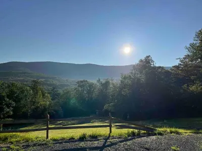 a field with a fence and the sun in the sky at Piebald Mountain Pet Friendly Tents, Petersburg, New York