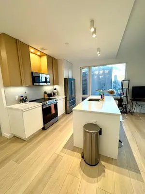 a kitchen with white cabinets and a large window at 5 mins to Midtown Central New Luxury Corner 2b2b Apt with Amazing City View in Long Island City